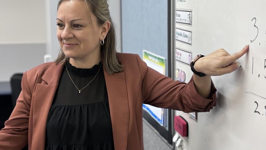 Educator Joanne Gibson pointing to number 3 on whiteboard.