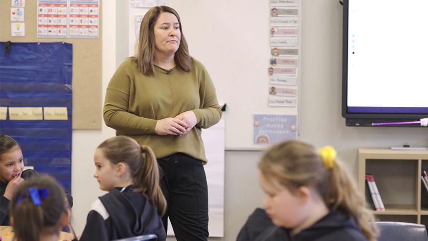 Teacher standing in front of class sitting at desks giving student the look