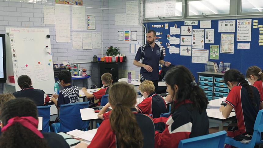 Teacher walking around classroom scanning students working at their desks