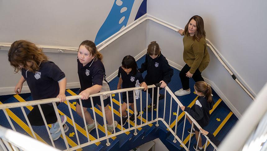 Teacher walking with students upstairs to another part of the school