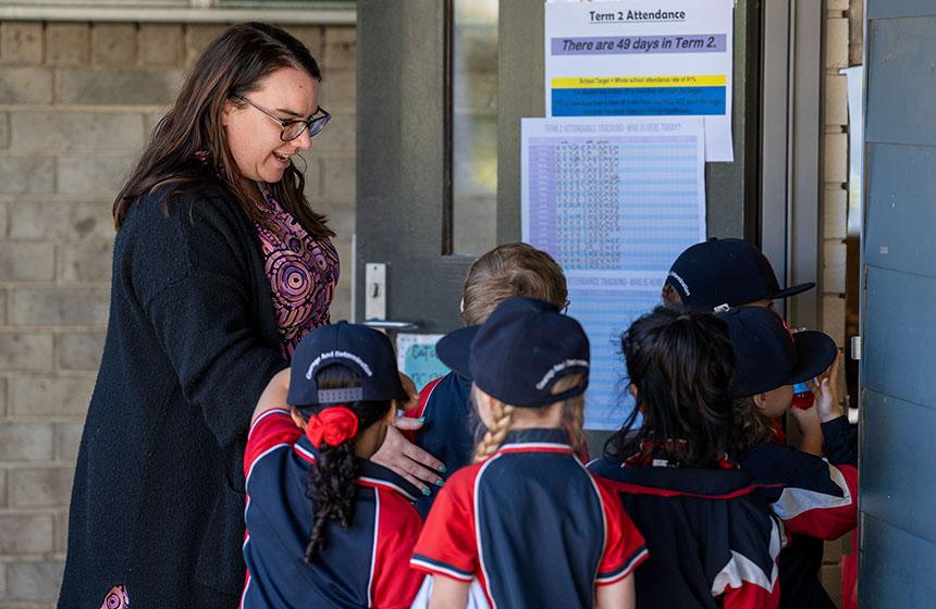 Teacher greeting students lining up at door as they enter the classroom